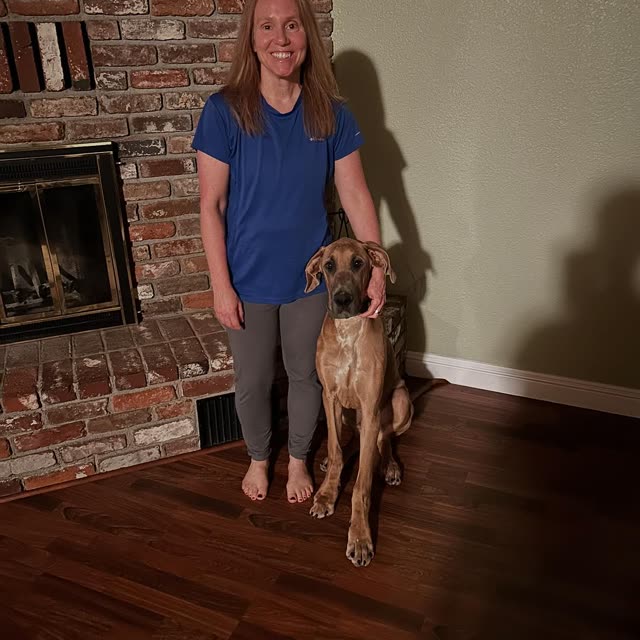 Stacey standing by the fireplace with her dog
