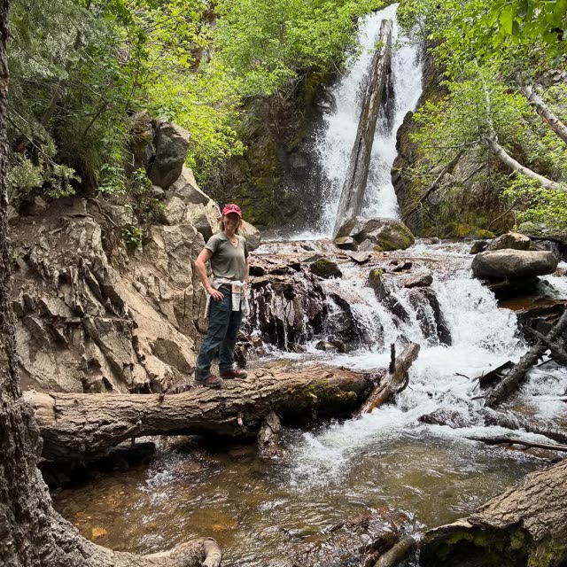Stacey on a rock beside a waterfall in the woods